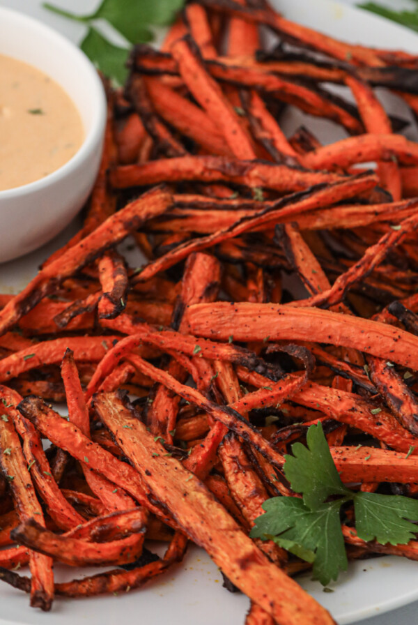 Carrot fries made in the air fryer and served on a plate with dipping sauce.