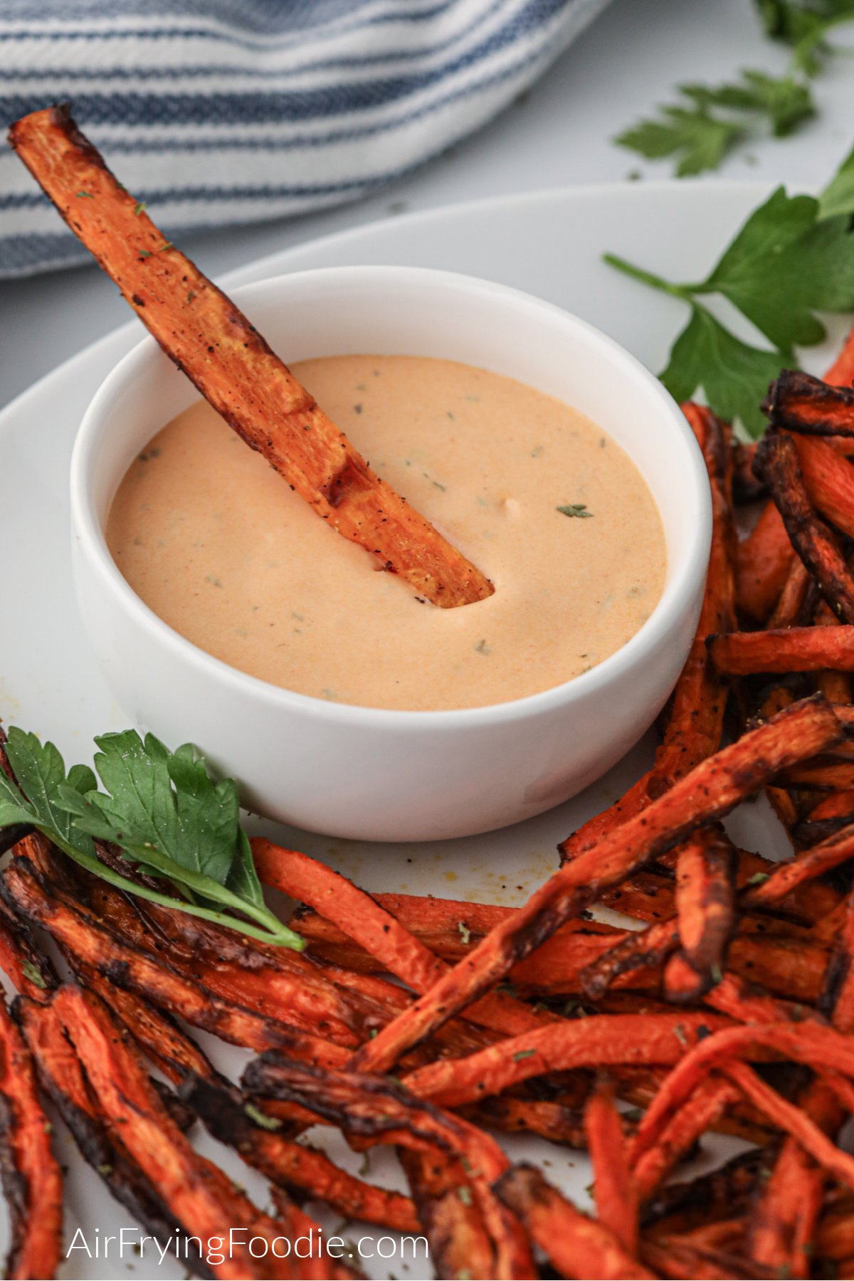 Crispy air fryer carrot fries on a plate and in dipping sauce. 