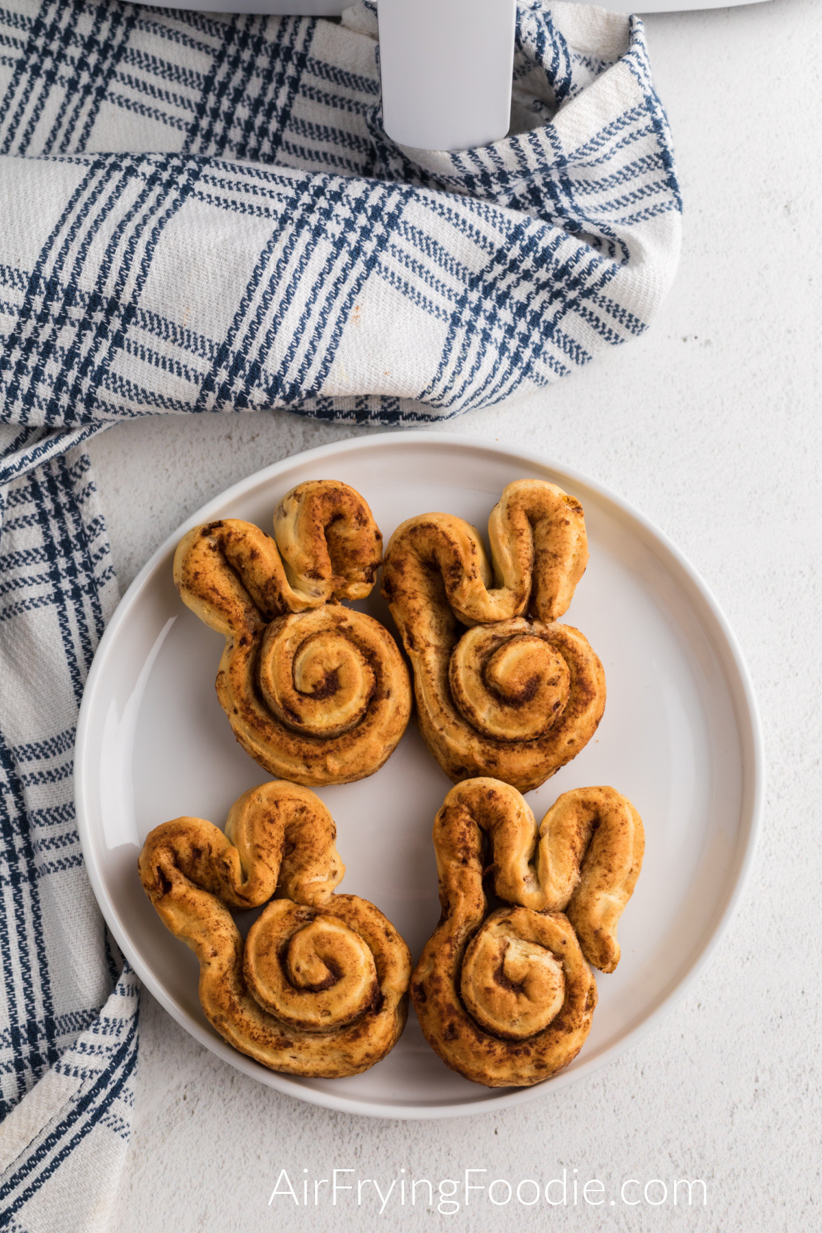 Cinnamon roll bunnies made in the air fryer and served on a white plate, ready to have glaze or frosting added.