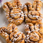 Air fryer cinnamon roll bunnies on a white plate and topped with glaze, ready to serve.
