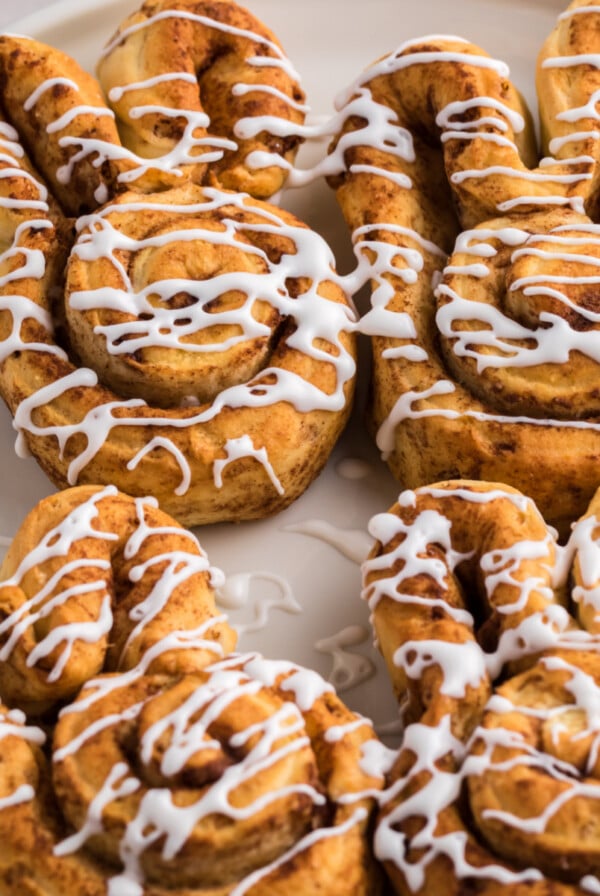 Air fryer cinnamon roll bunnies on a white plate and topped with glaze, ready to serve.