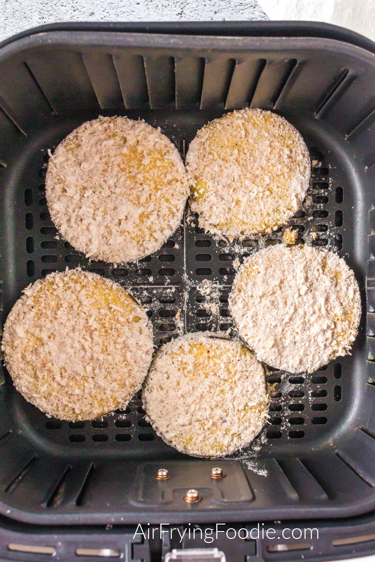 Breaded sliced eggplant in the basket of the air fryer ready to be cooked. 