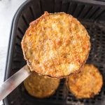 Cooked and crispy Air fryer eggplant being lifted out of the basket of the air fryer.