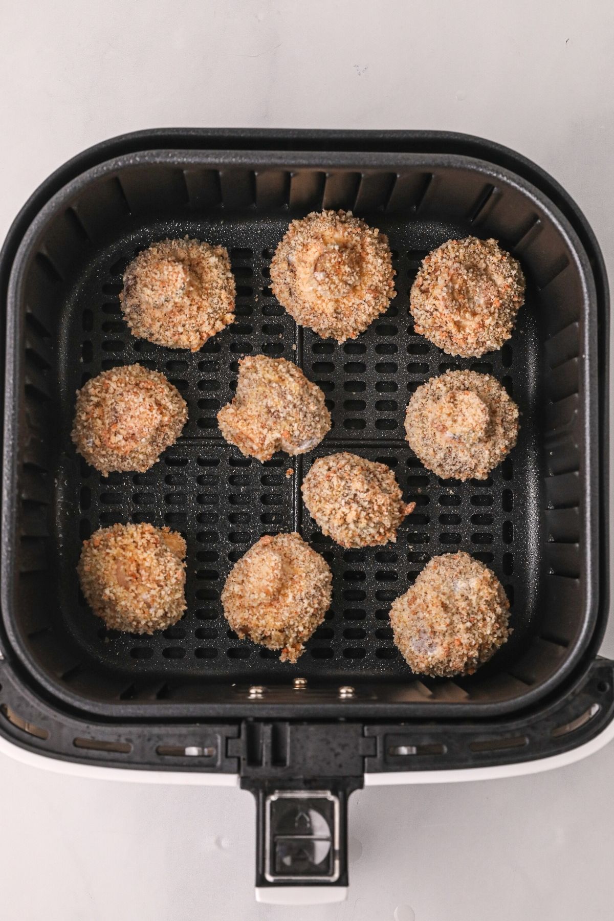 Battered mushrooms in the air fryer basket before being cooked