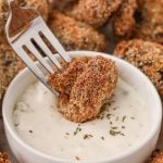 Golden brown fried mushroom being dipped into ranch dressing