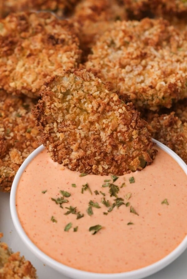 Air fried pickles being dipped into a sauce