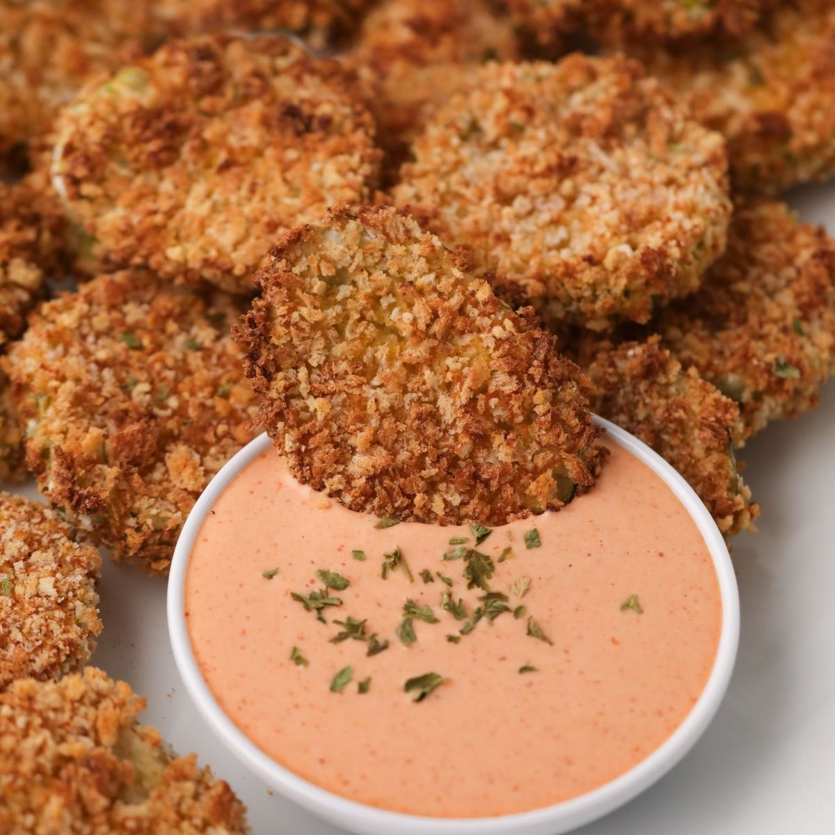Air fried pickles being dipped into a sauce