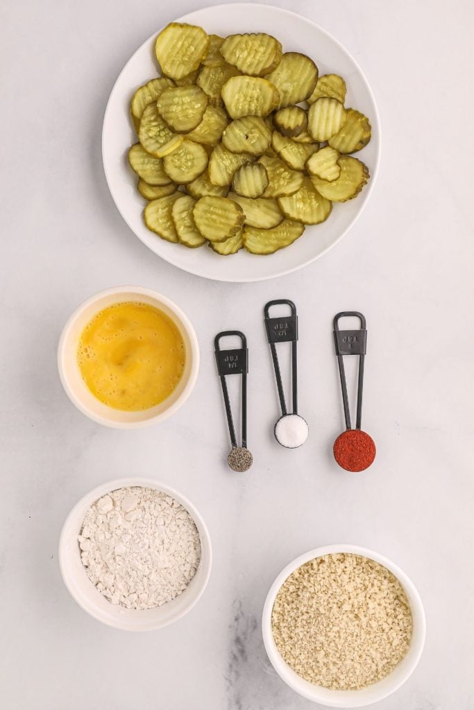Ingredients needed to make fried pickles, measured out on a white board. 