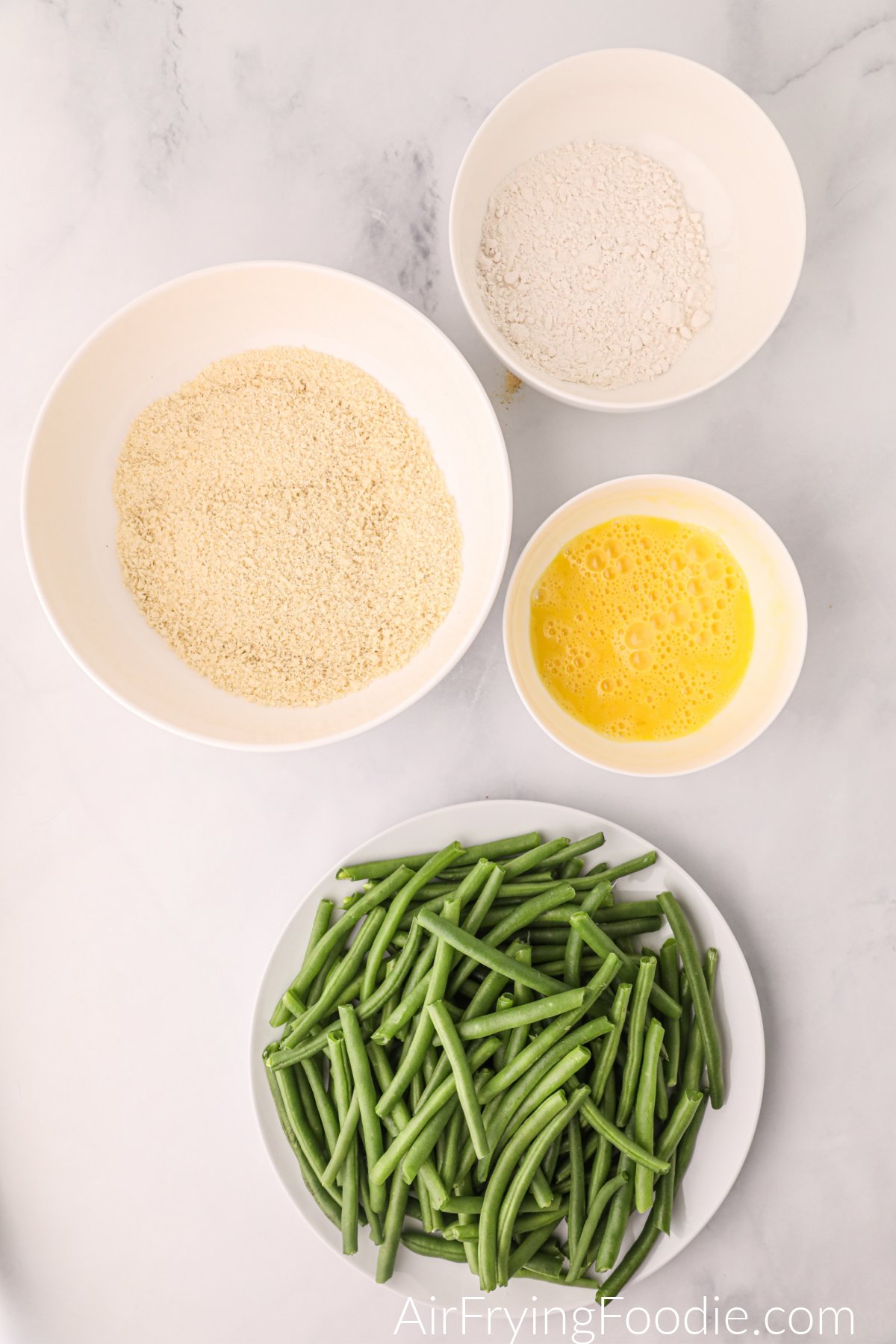 green beans in a bowl, eggs, seasoning, and mix to make green bean fries in the air fryer.
