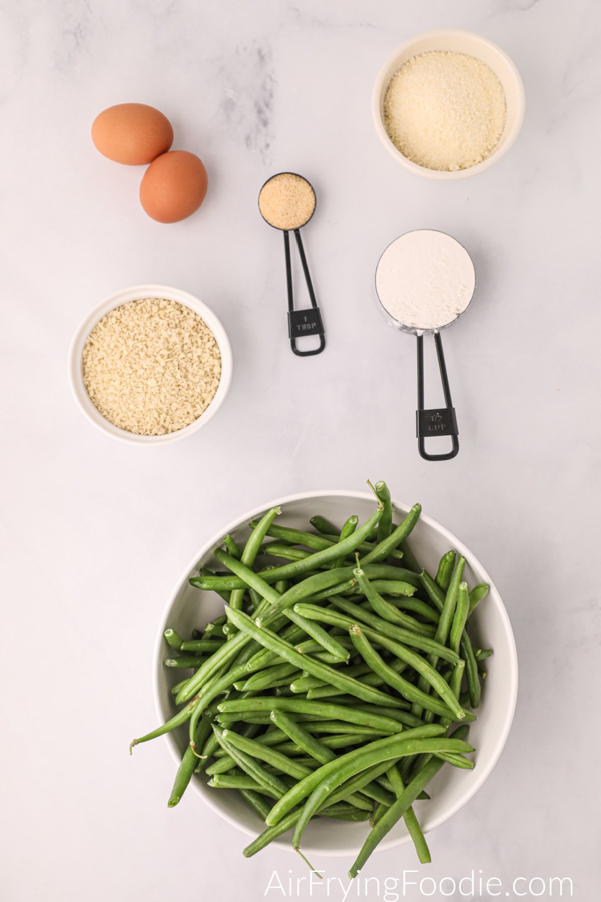 green beans in a bowl and other ingredients to make green bean fries in the air fryer.