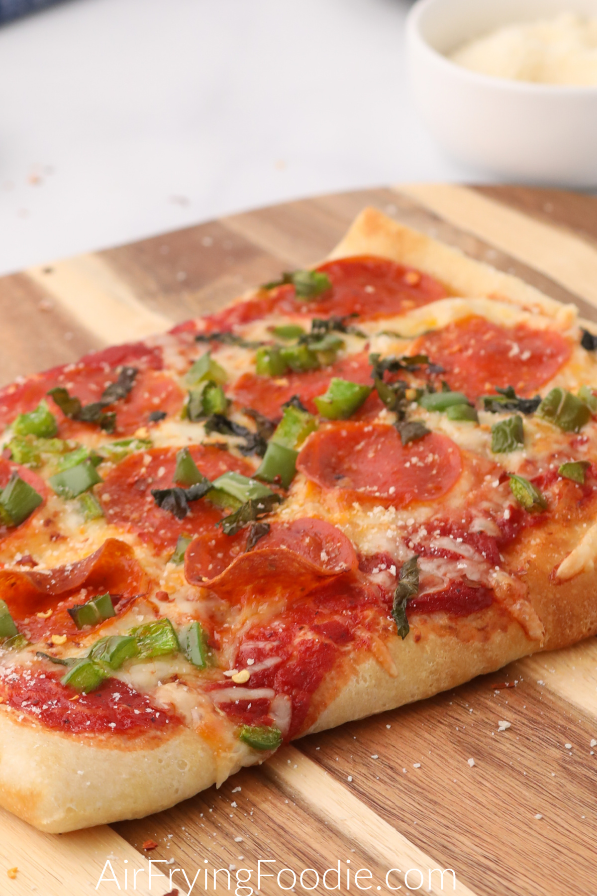 Fully cooked air fryer pizza on a cutting board and ready to serve. 