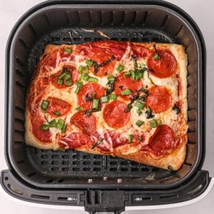 Homemade air fryer pizza in the basket of the air fryer, ready to serve.