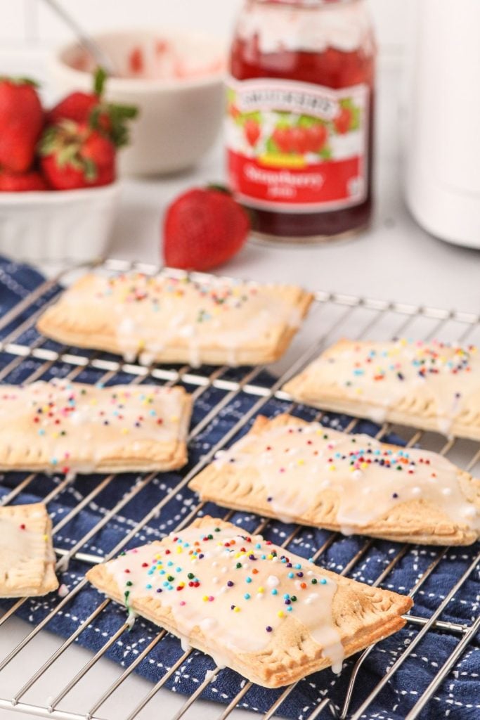 Golden pop tarts on a cooking rack after being cooked and lightly glazed with sprinkles