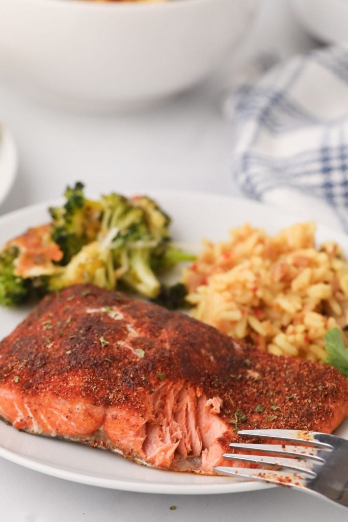 Flaky cooked salmon on a white place with rice and broccoli