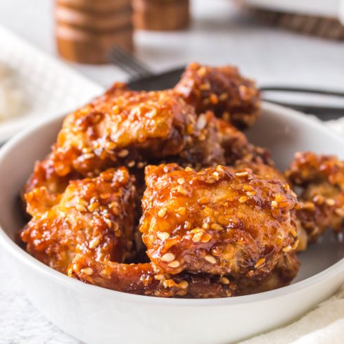 Air fried sesame chicken in a white bowl and ready to serve.