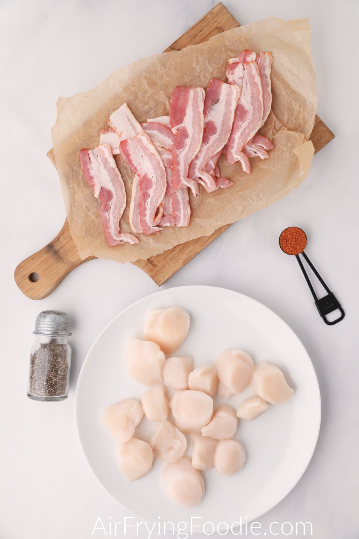 Ingredients needed to make bacon wrapped scallops in the air fryer - layed out on a table ready to be put together.