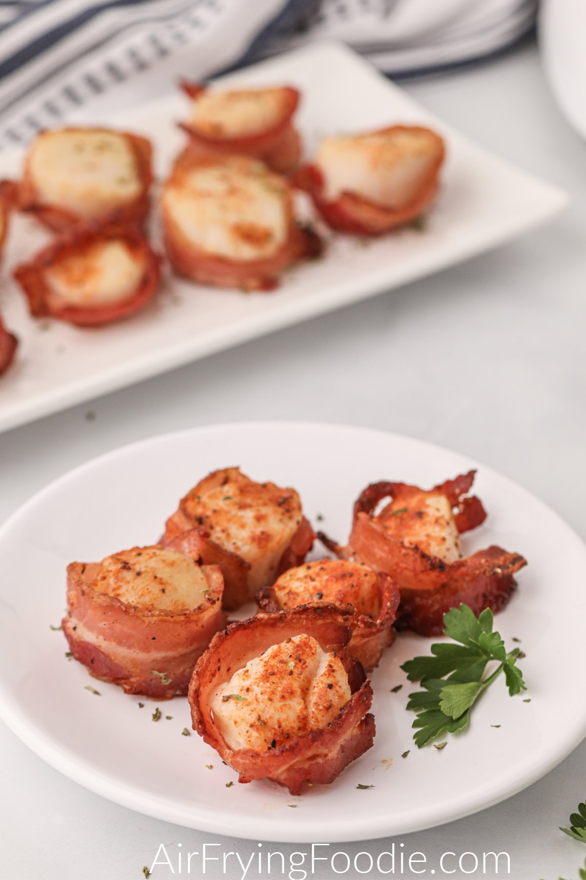 Air fryer bacon wrapped scallops on a white plate ready to serve.