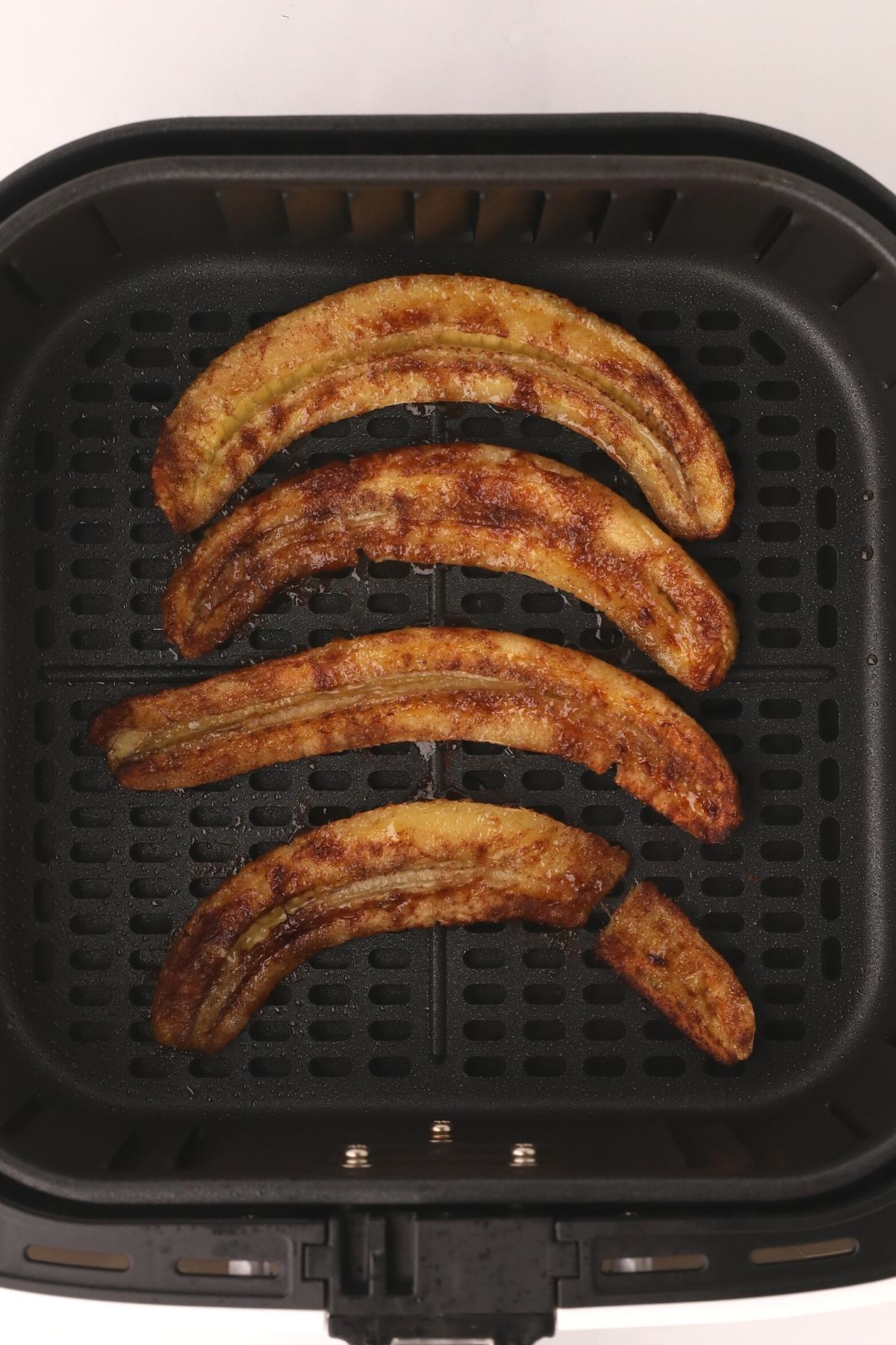 Seasoned bananas in the air fryer basket after being cooked