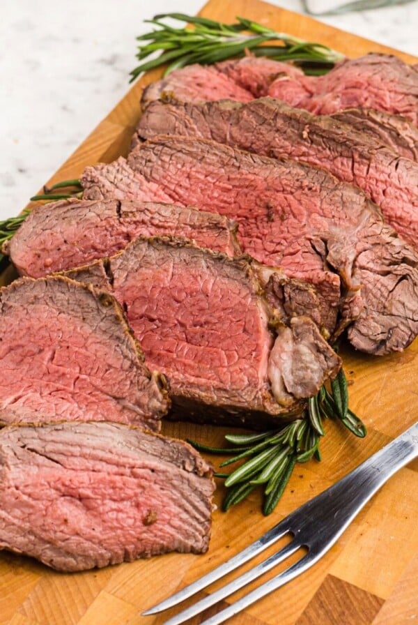 Juicy cuts of tenderloin on a cutting board in front of an air fryer