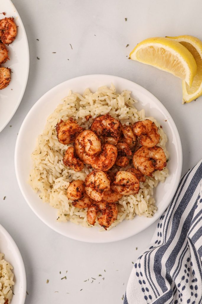 Cajun shrimp over rice on a white bowl served on a white marble table