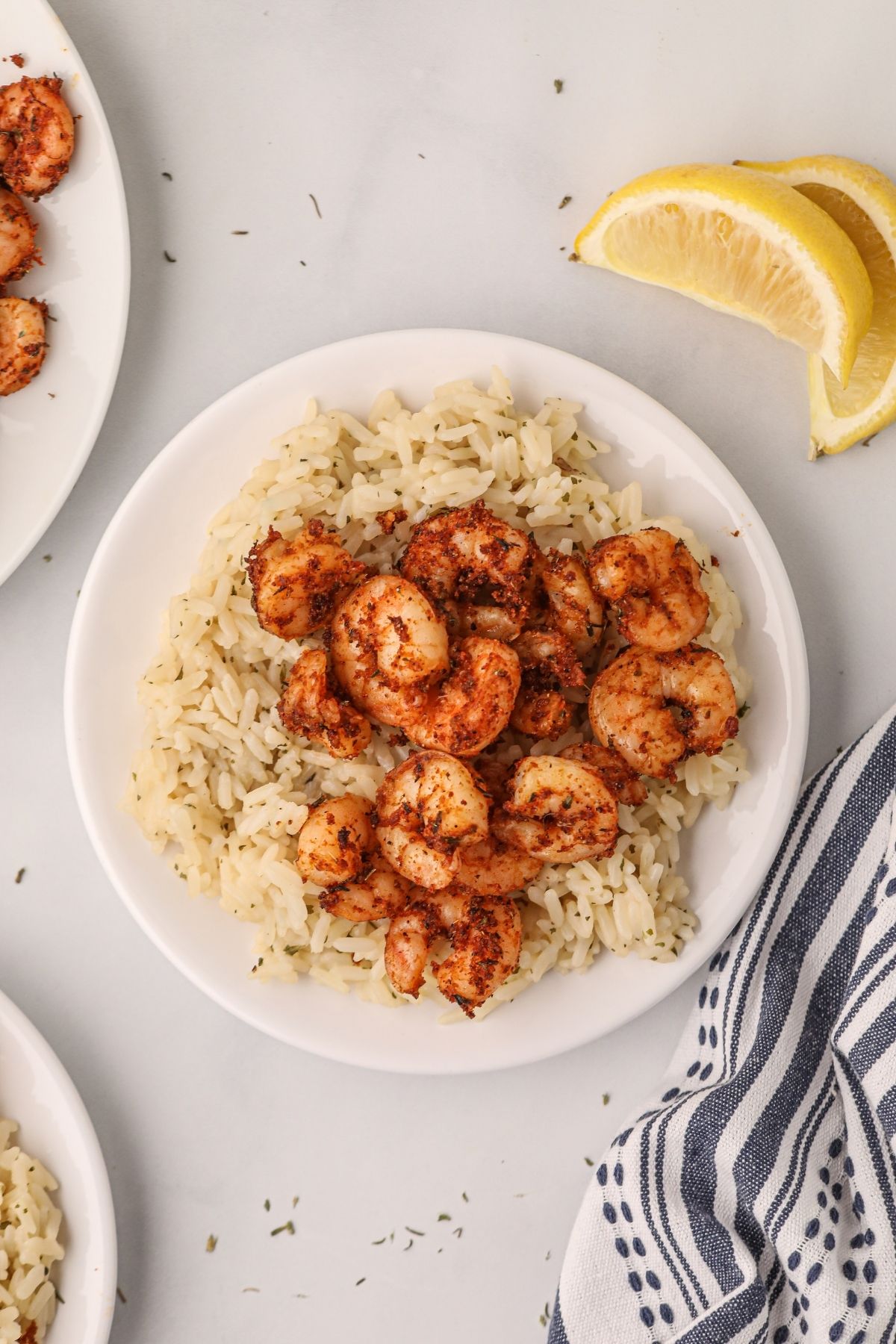 Cajun shrimp made in the air fryer, served over rice on a white plate. 