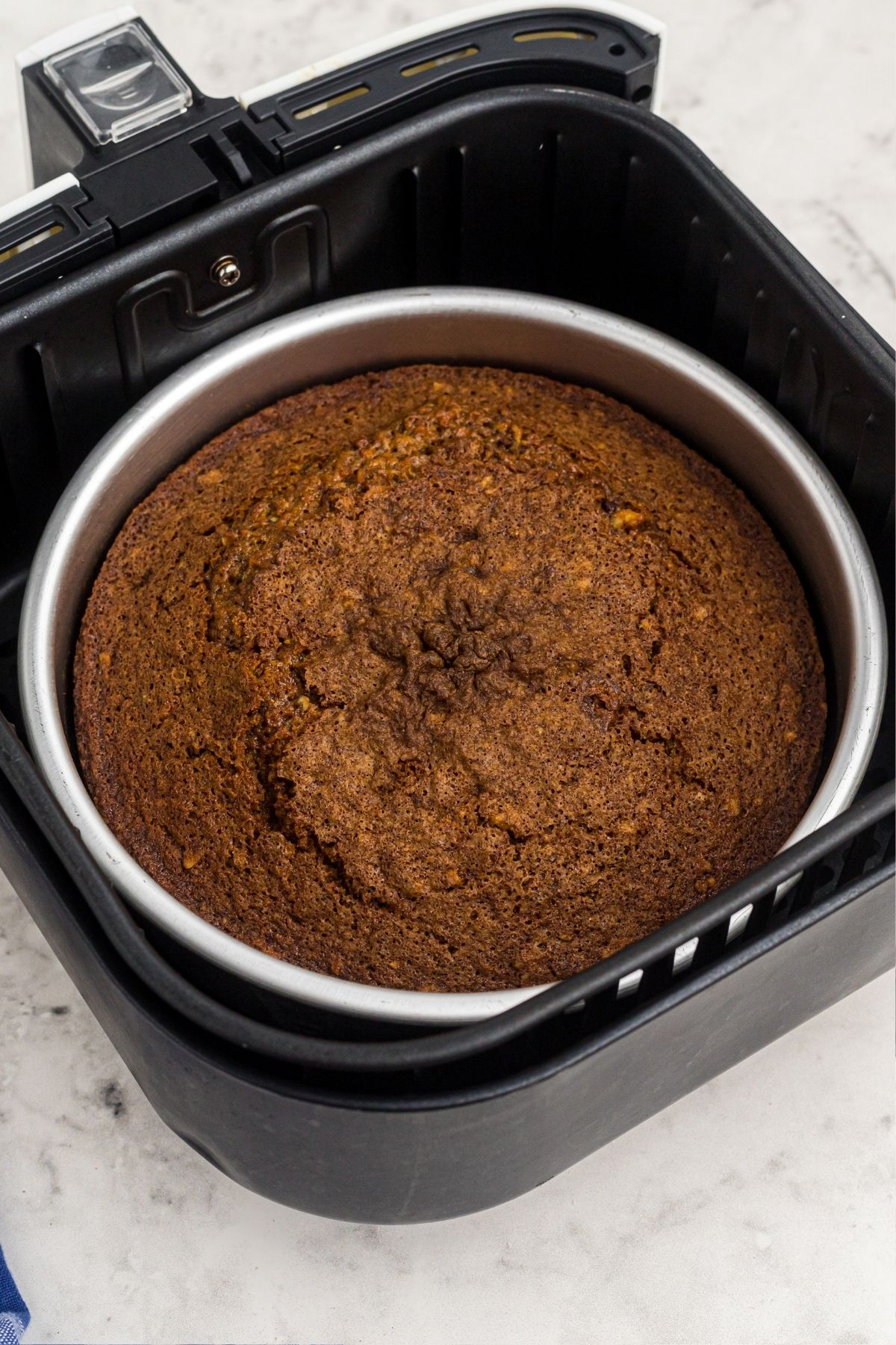 cooked cake in the air fryer basket in a round cake pan