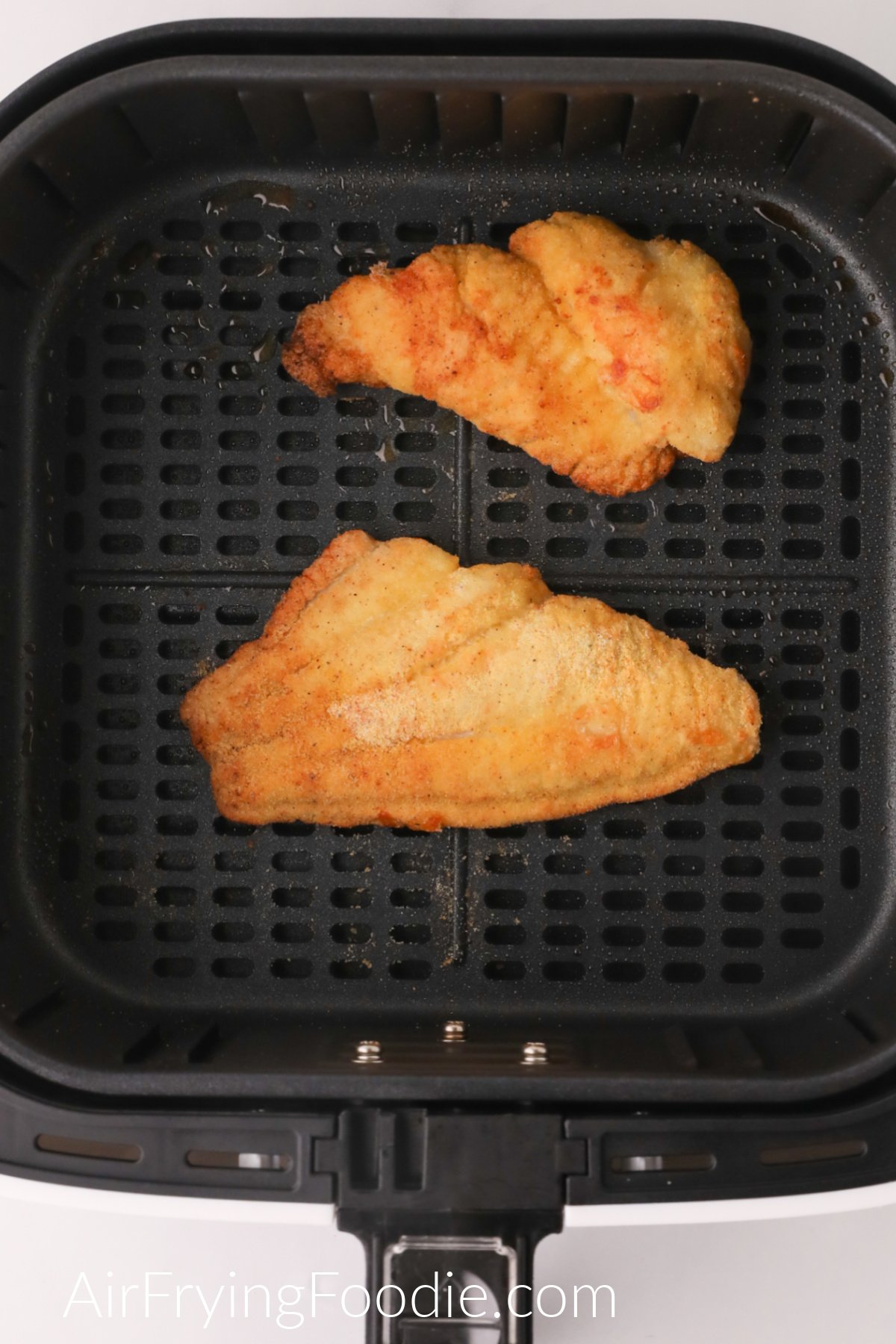 Air fried catfish in the basket of the air fryer, ready to serve.