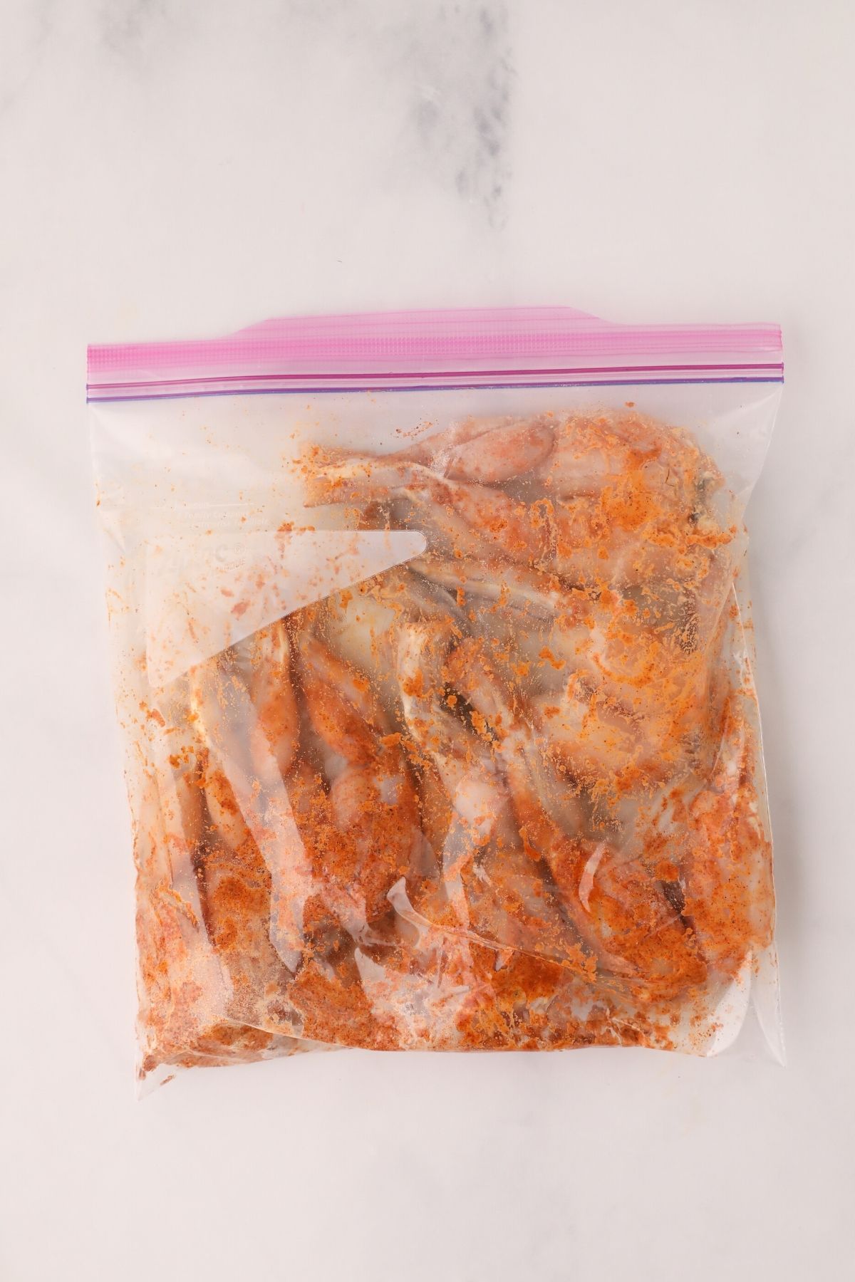 Seasonings mixed into a large bag with frog legs to season