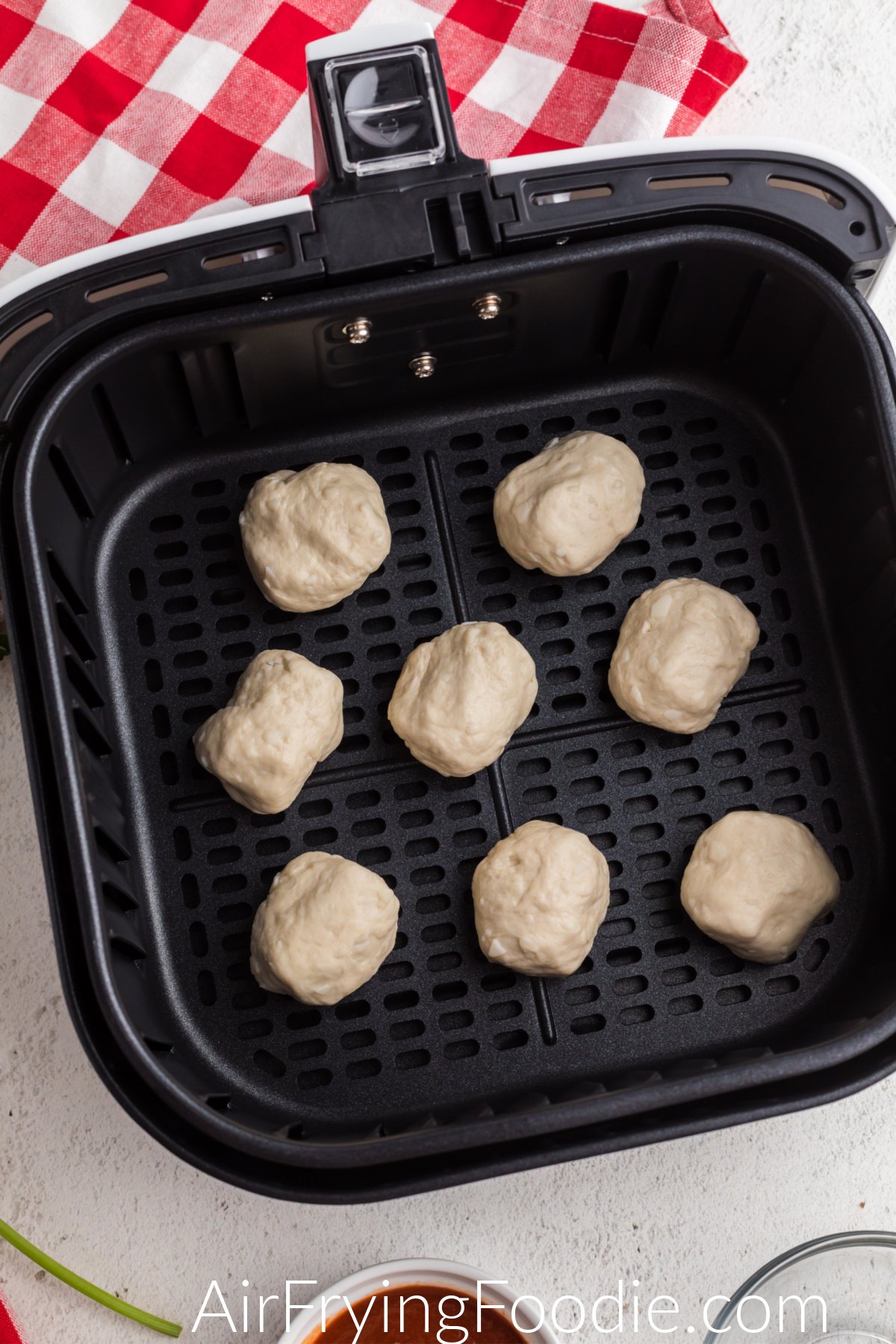 Mozzarella balls in a single layer in the basket of the air fryer.