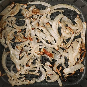 Crispy air fried onions in the basket of the air fryer.