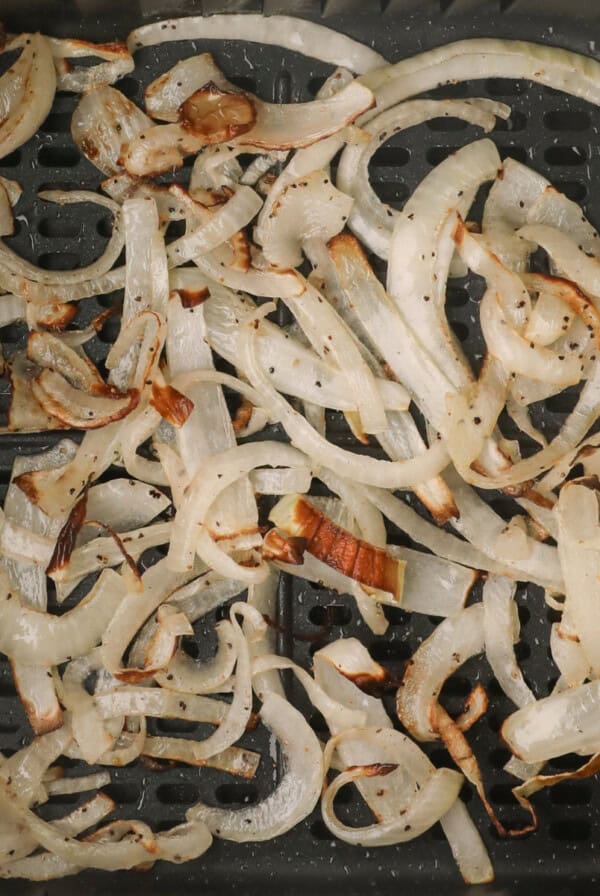 Crispy air fried onions in the basket of the air fryer.