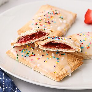 Golden pastries filled with strawberry jam, on a white plate.