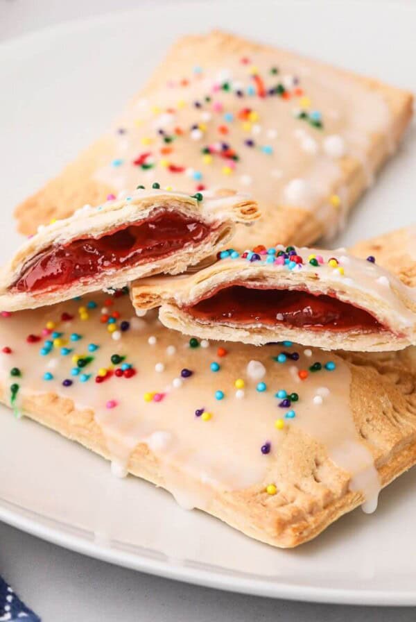 Golden pastries filled with strawberry jam, on a white plate.