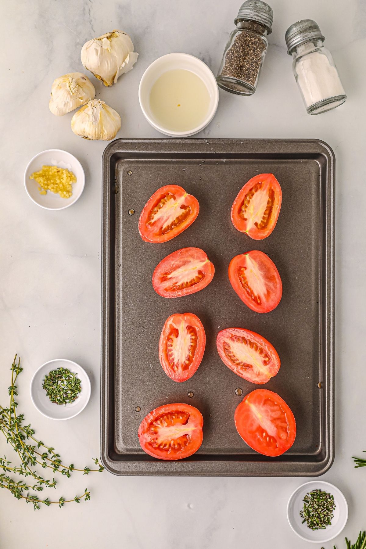tomatoes sliced in half on a baking sheet.