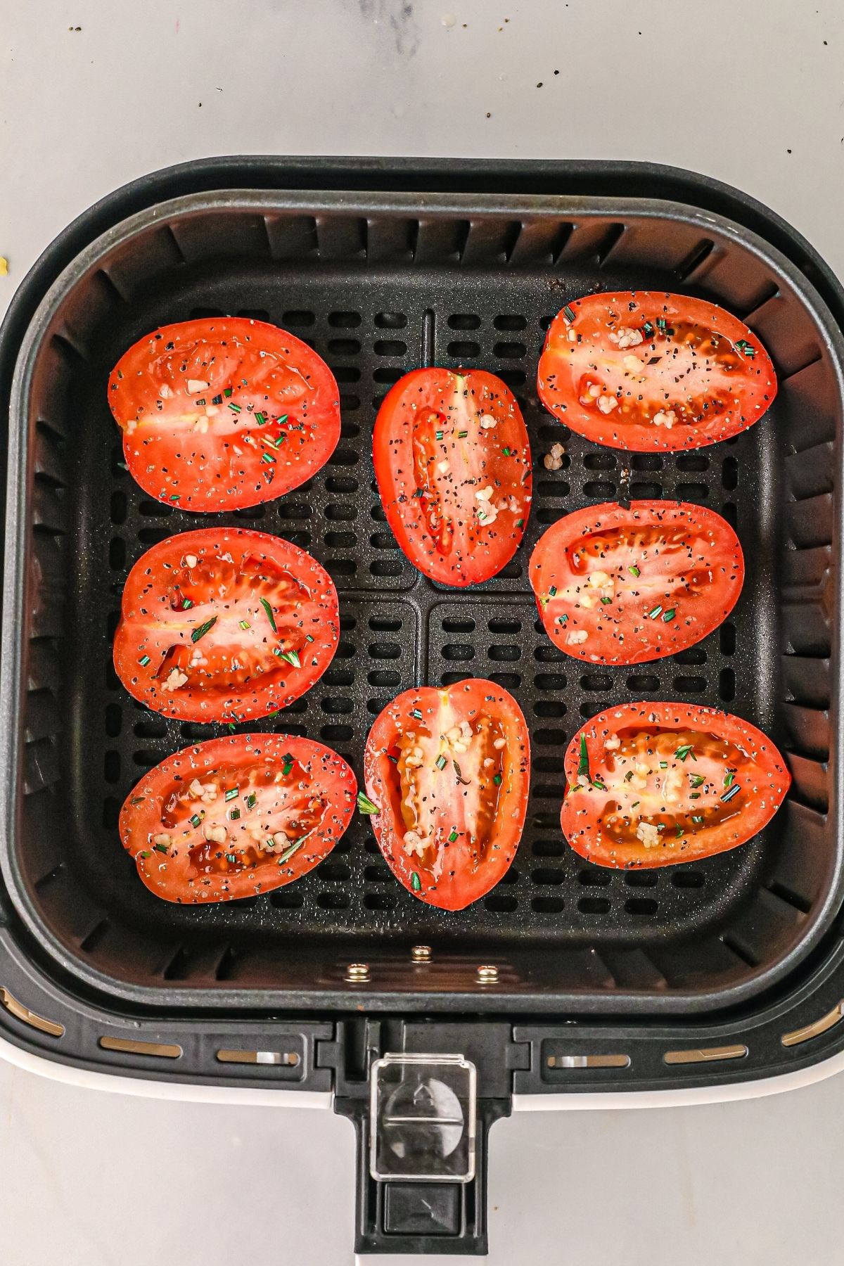 uncooked tomatoes in the air fryer basket before being cooked. 