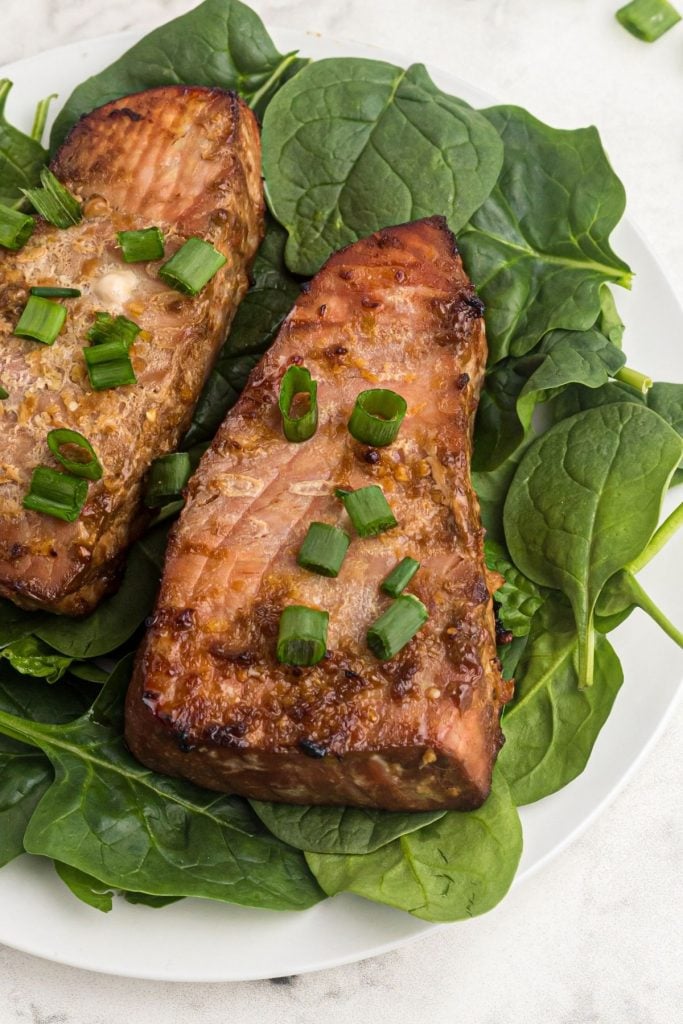 Juicy tuna steaks seasoned and cooked on a bed of spinach. Garnished with green onions