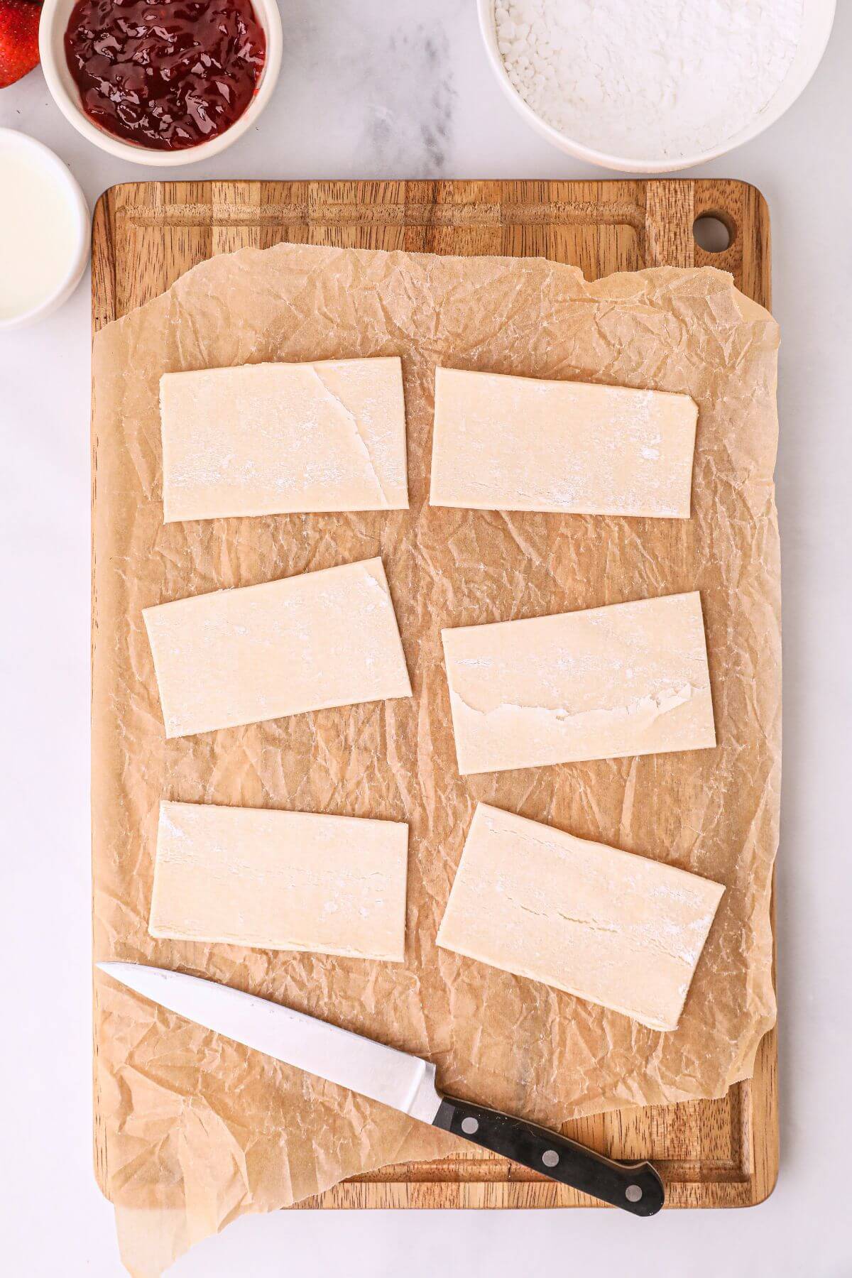 Pastry sheet cut into rectangles on a cutting board. 