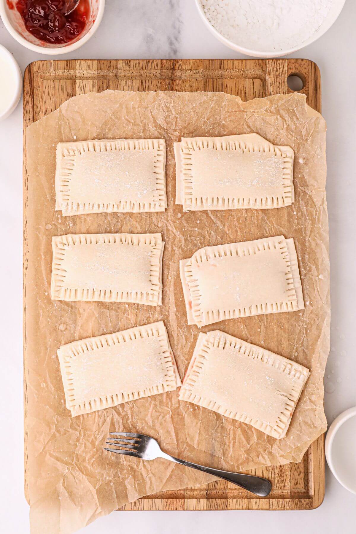 Pastry rectangles filled with jam, with corners pinched and sealed with a fork. 