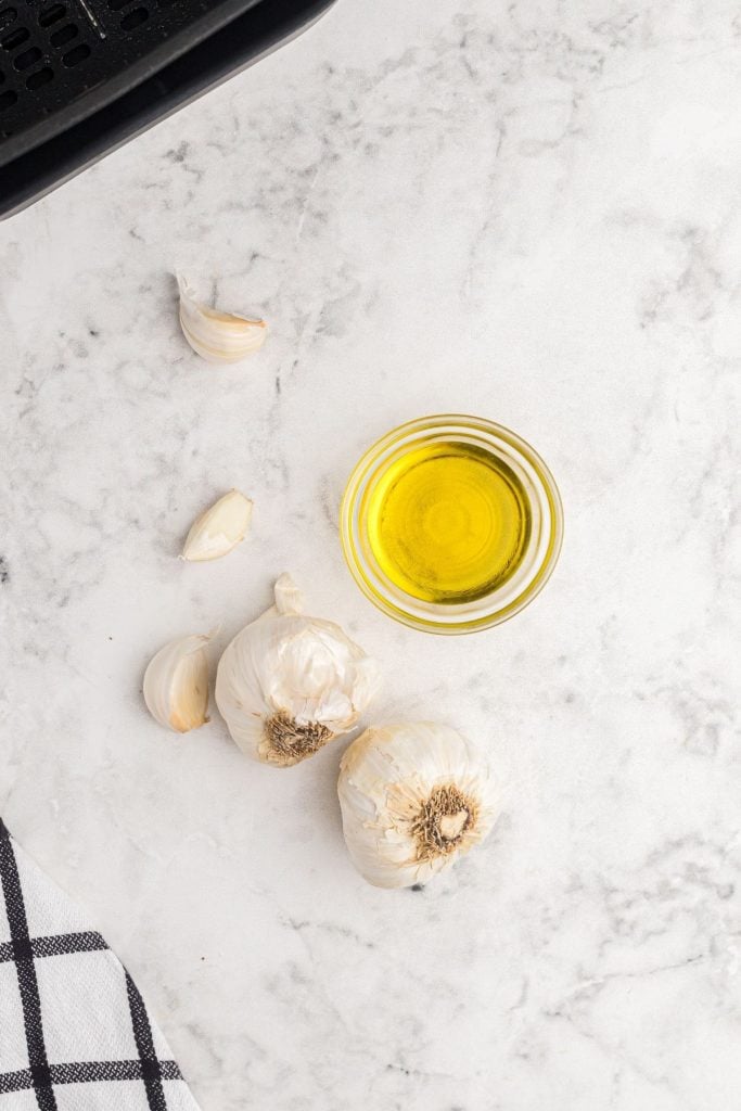 Garlic bulbs and olive oil on a white marble talble