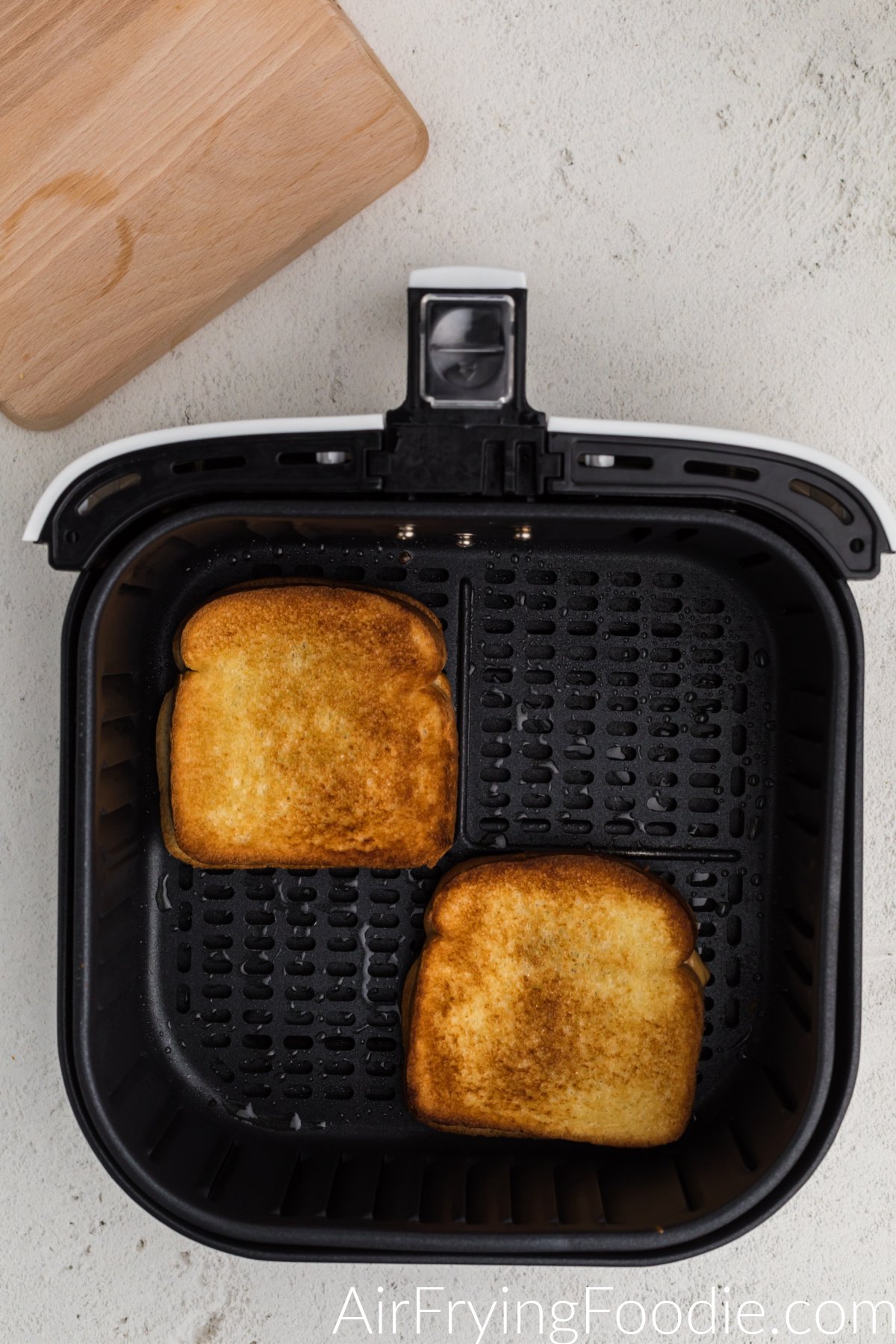 Golden brown air fried peanut butter and jelly sandwiches in the air fryer basket.