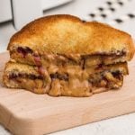 sliced fried peanut butter and jelly sandwich made in the air fryer, golden brown and with melted peanut butter and jelly oozing onto the cutting board.
