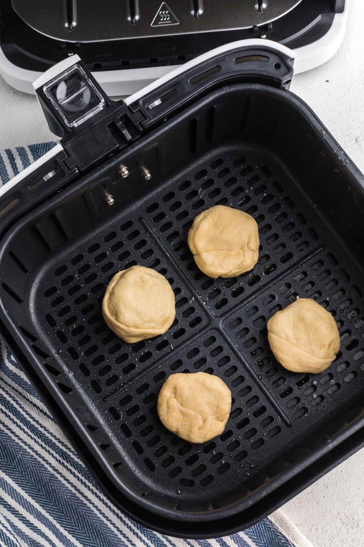 Raw dough wrapped around peanut butter cups in the air fryer basket