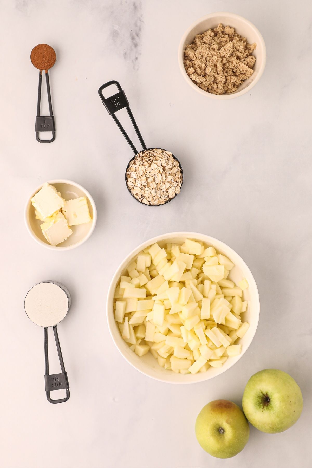 apples cut and sliced in a bowl along with filling ingredients measured out on a white marble table