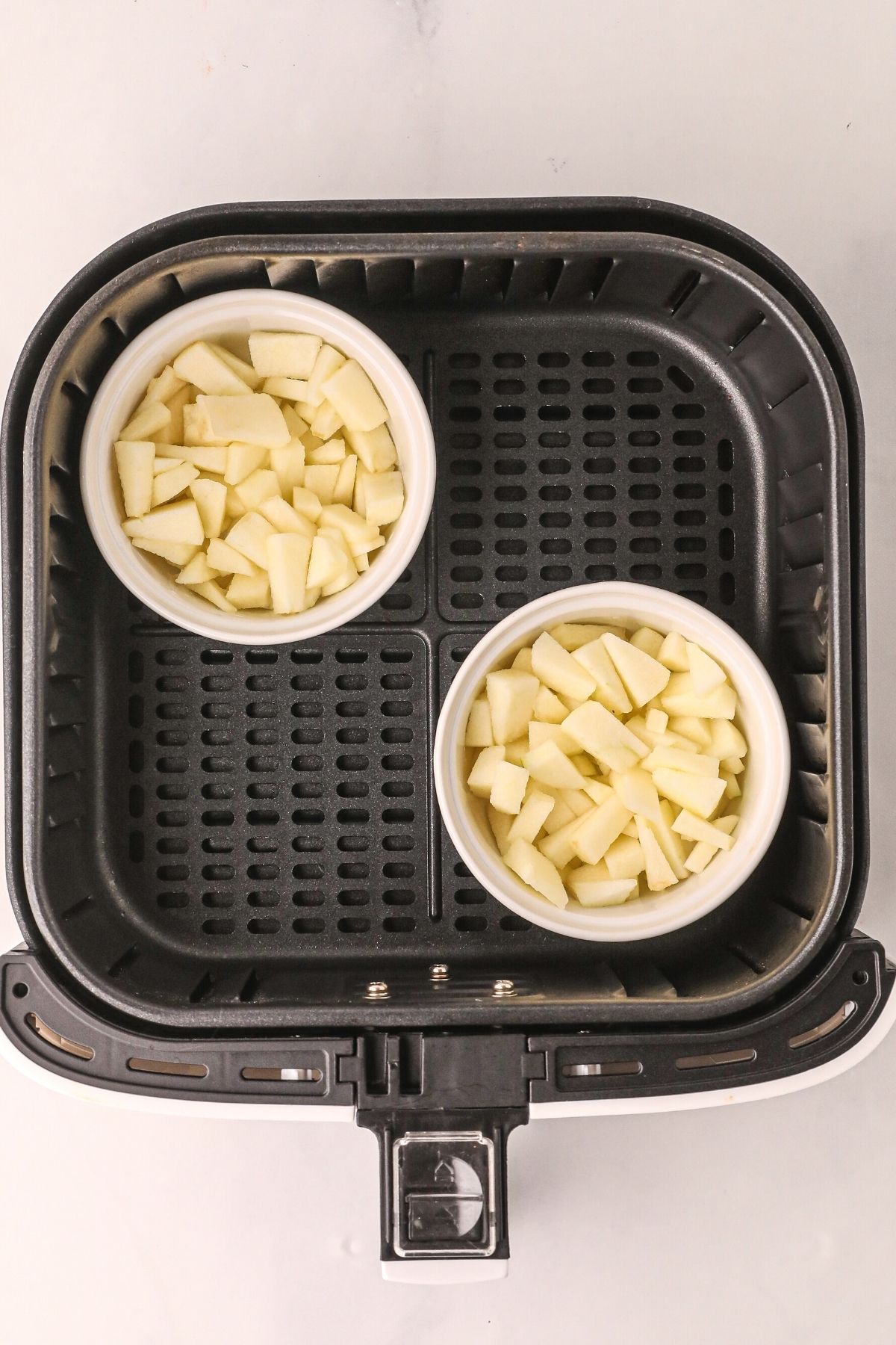 apple mixture placed in ramekins and then in placed in an air fryer basket before cooking