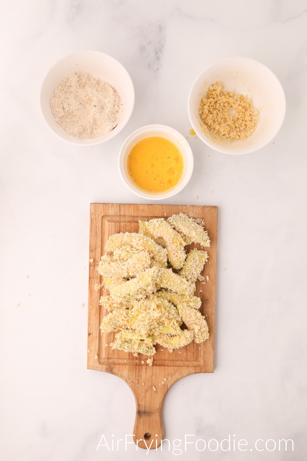 Avocado fries dipped into breadcrumb and egg mixtures before cooking.