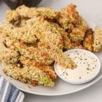 Avocado fries made in the air fryer and served on a white plate with dipping sauce on the side.