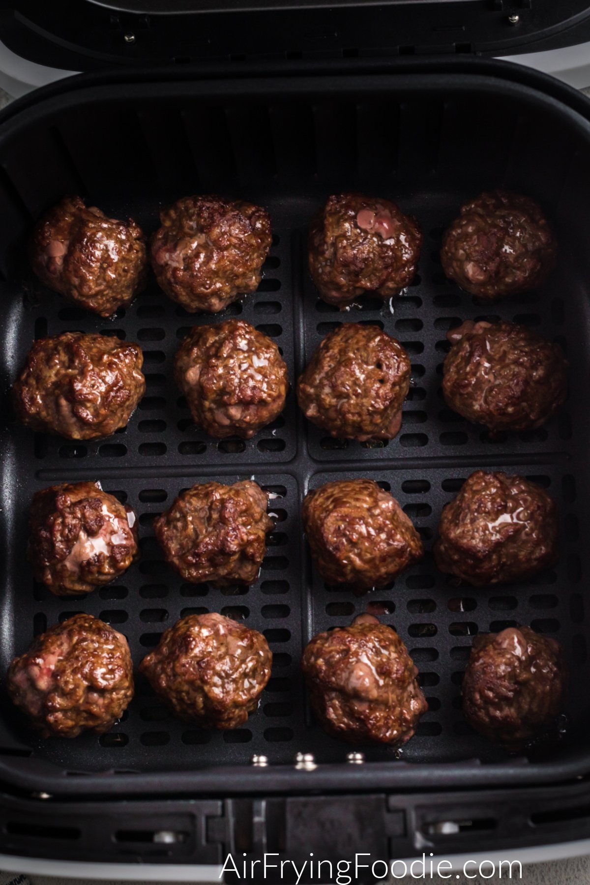 Cooked meatballs for cheeseburger bombs in the basket of the air fryer.