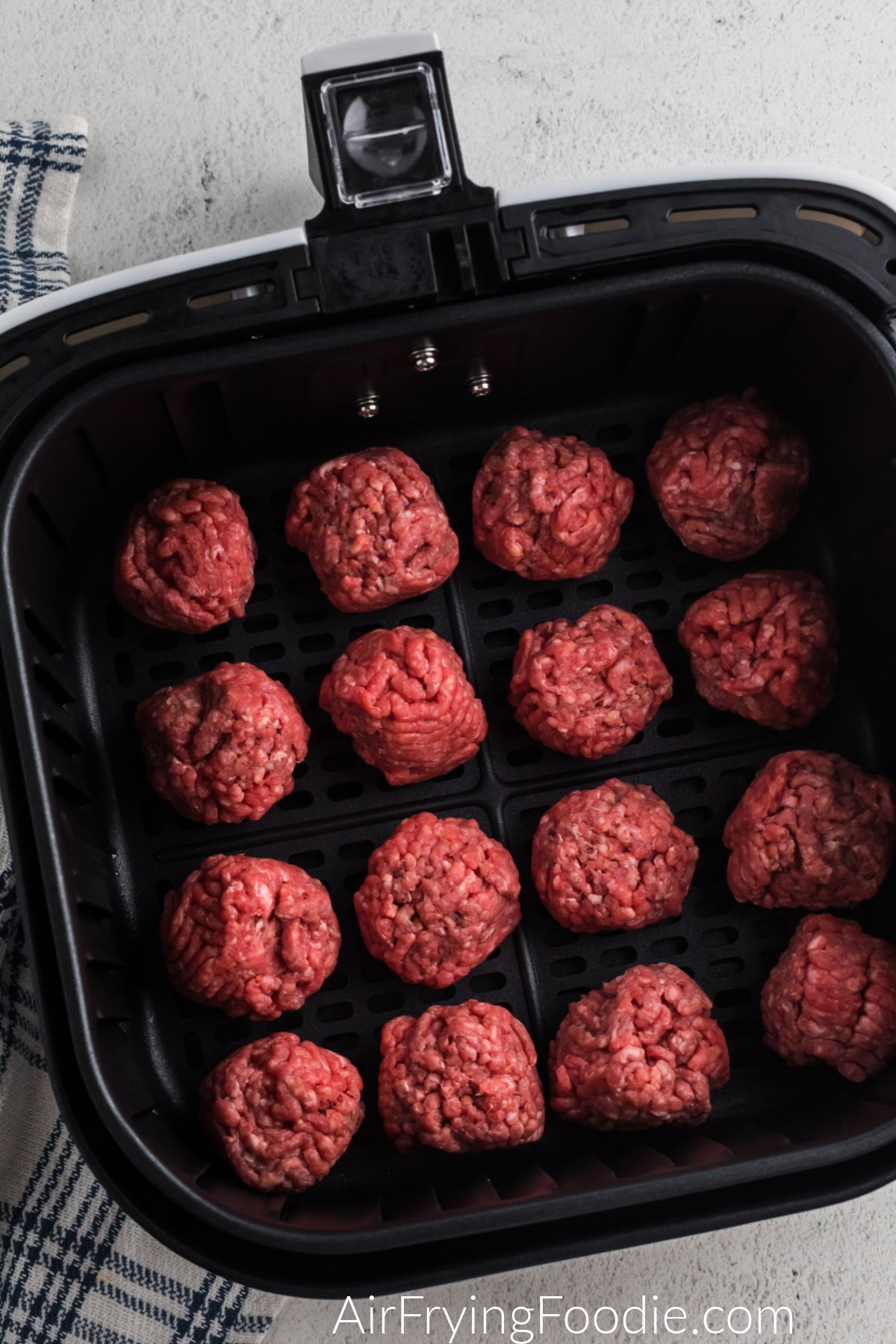 Homemade meatballs in the basket of the air fryer for cheeseburger bombs