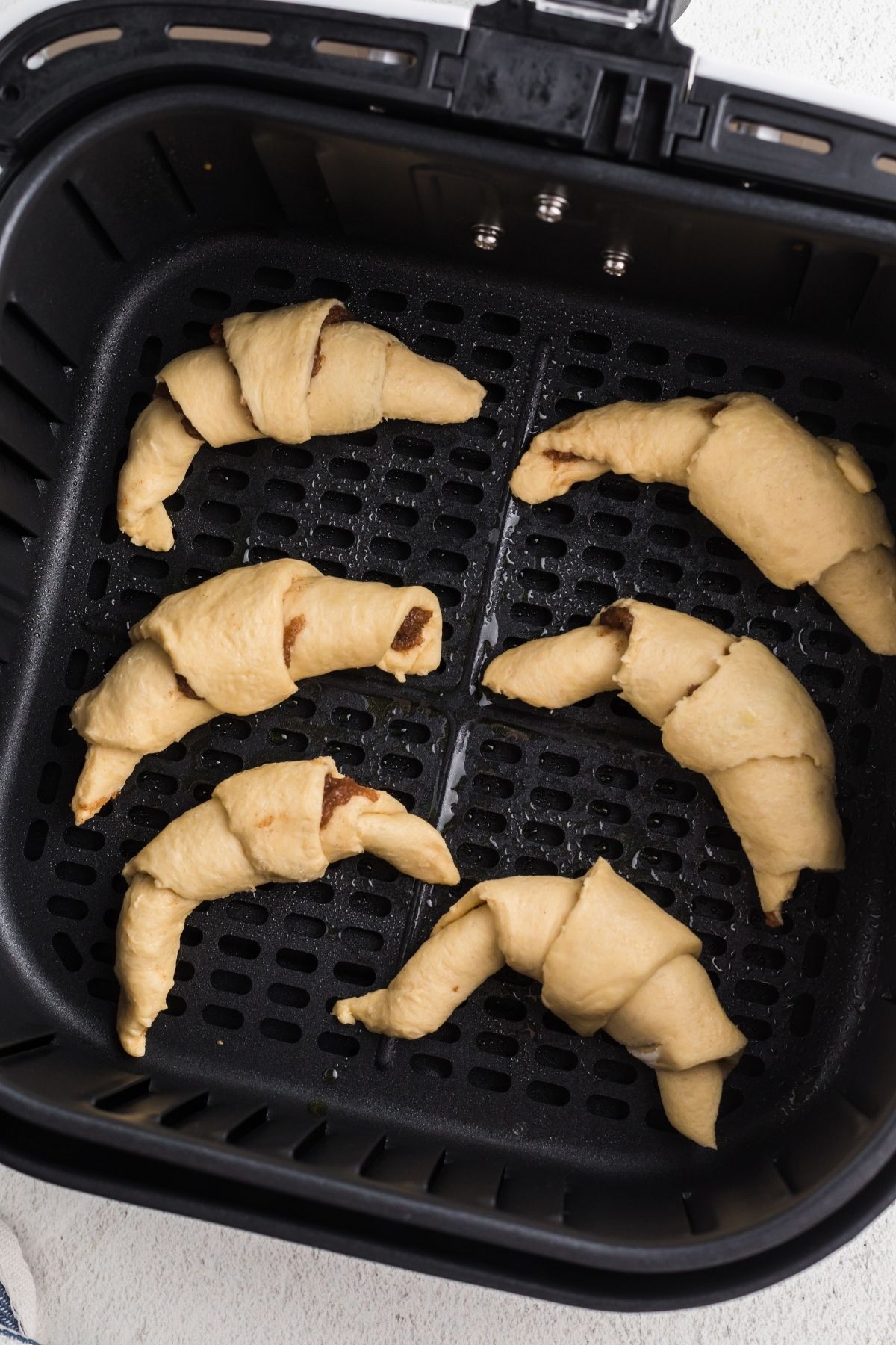 uncooked cinnamon filled crescent rolls in the air fryer basket