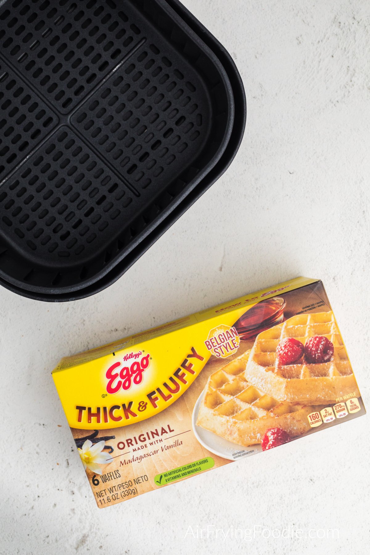 Picture of frozen eggo waffles in the box and an air fryer basket. 